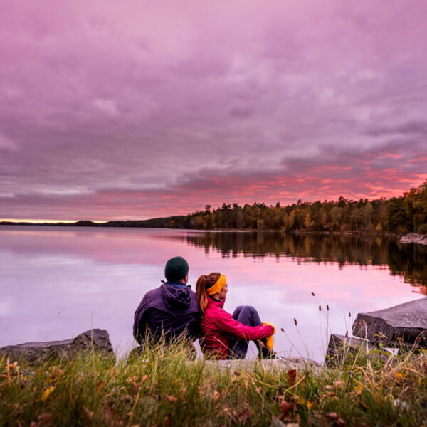 south of sweden lade with a pink sunset and two tourists sitting on the shoreline